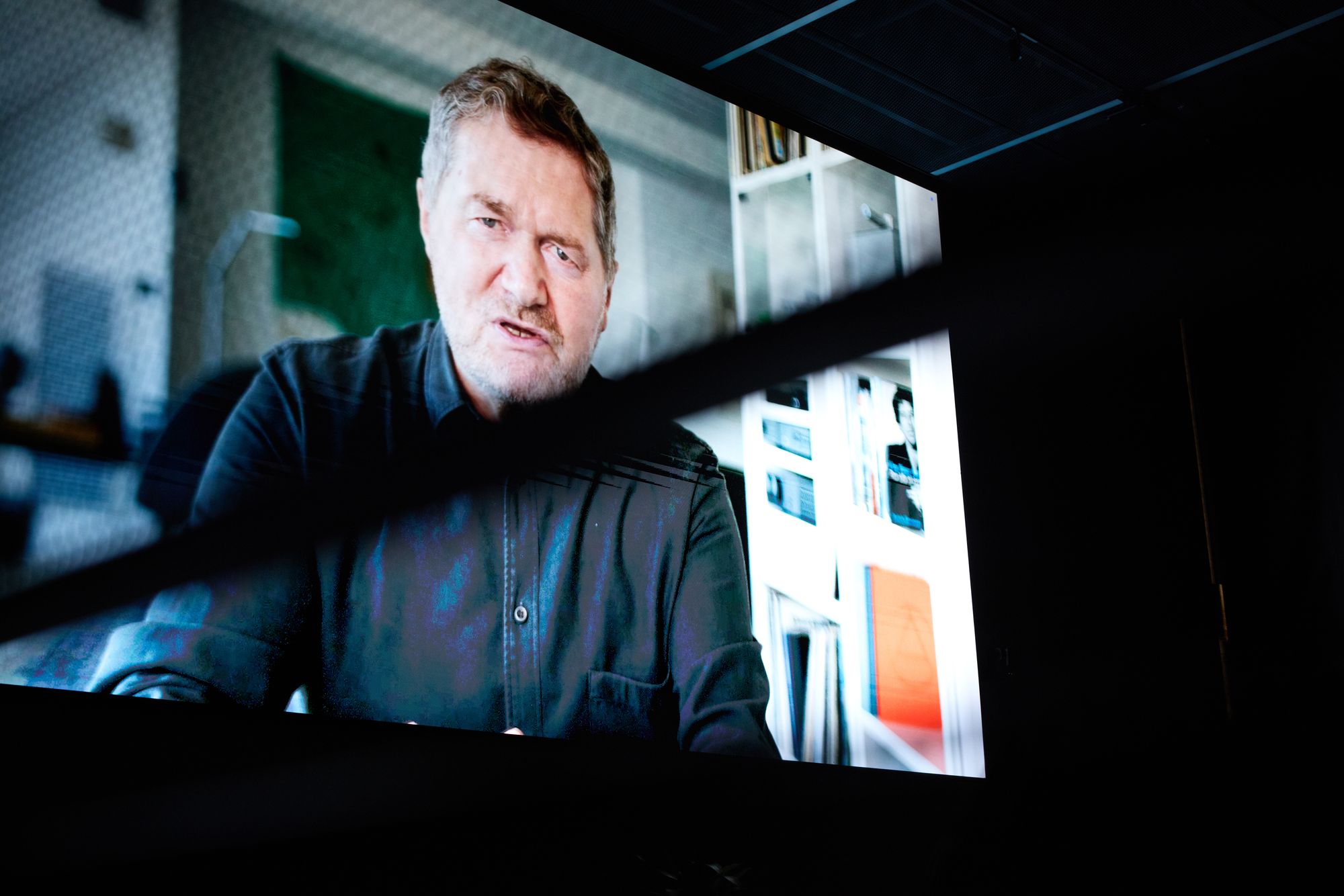 A still of the film screening; Patrick speaking to the camera.